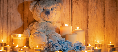 Image of a teddy bear with lit candles all around